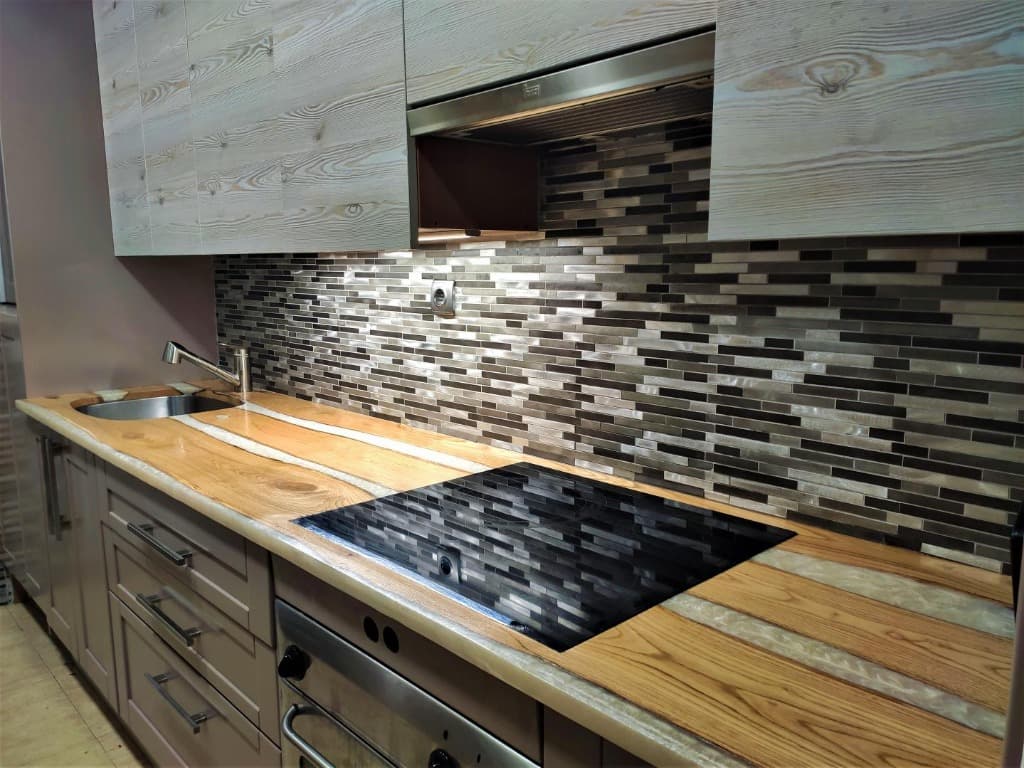 Encimera de cocina artesanal de madera maciza con vetas de resina epoxi perlada, placa de inducción y fregadero integrados, hecha a mano en Carpintería Cardiel, Binéfar
