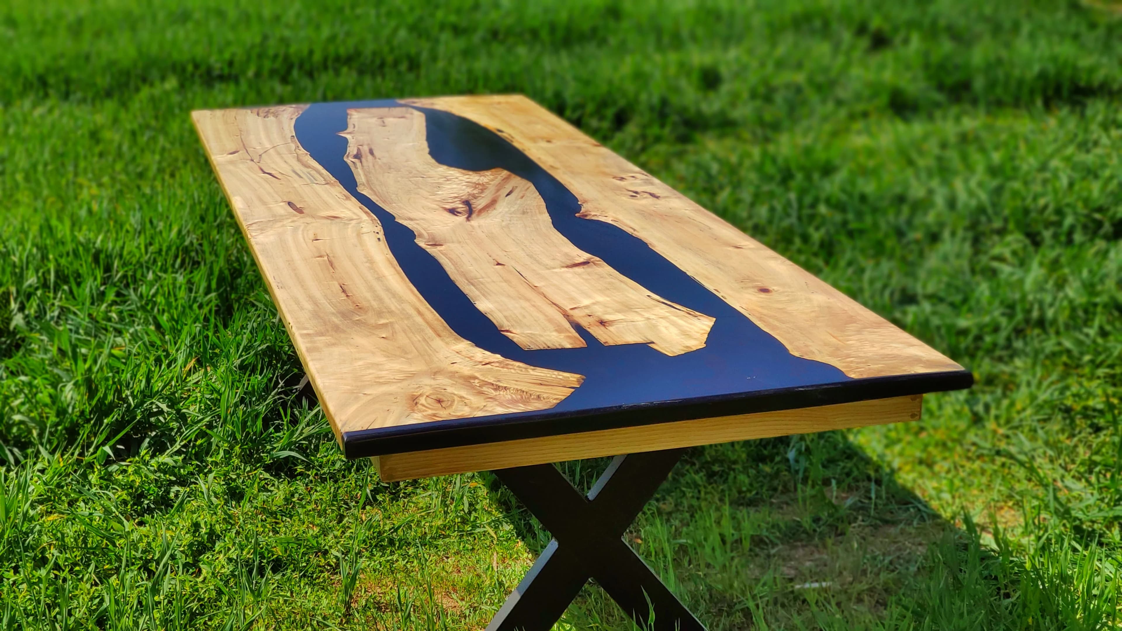 Mesa de comedor artesanal con río de resina epoxi negra sobre madera noble en jardín, Carpintería Cardiel, Binéfar
