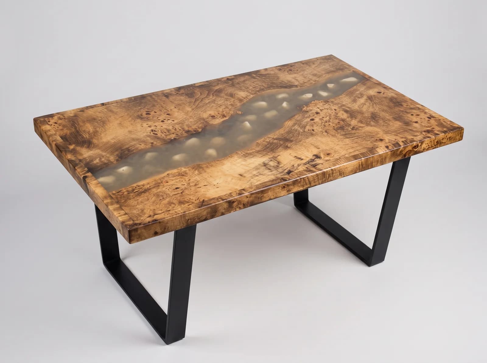Mesa de centro de madera noble y resina epoxi ámbar con cantos rodados en estudio