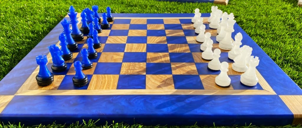 Tablero de ajedrez artesanal con resina azul eléctrico y madera de olivo, piezas azules y blancas, hecho a mano en Carpintería Cardiel Binéfar