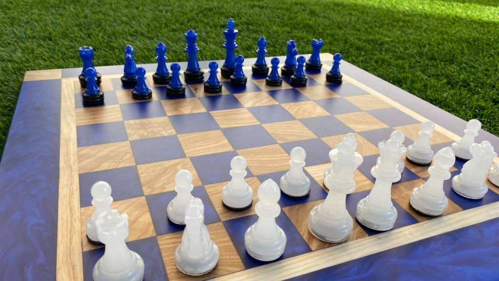 Tablero de ajedrez con resina lavanda y madera de olivo, piezas azules y blancas translúcidas, artesanal de Carpintería Cardiel Binéfar