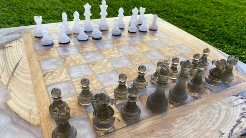 Tablero de ajedrez con resina blanca nacarada y piezas bronce translúcidas sobre madera con corte natural, Carpintería Cardiel Binéfar